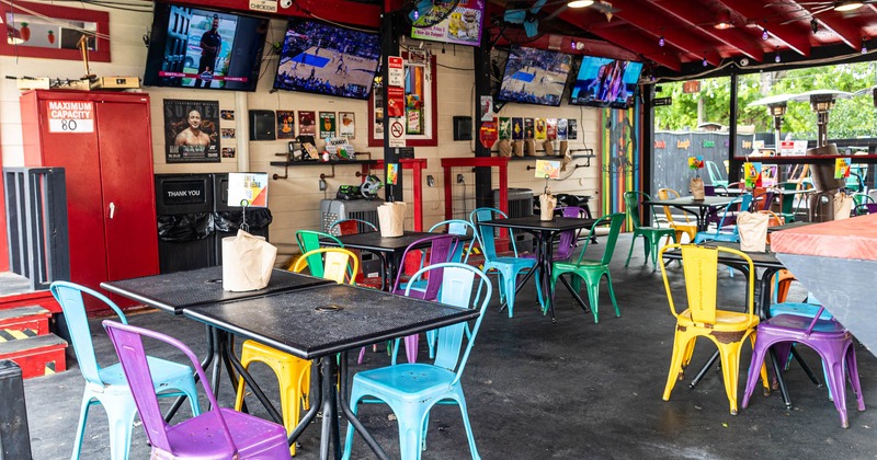 Covered terrace with chairs and tables, TVs on the wall
