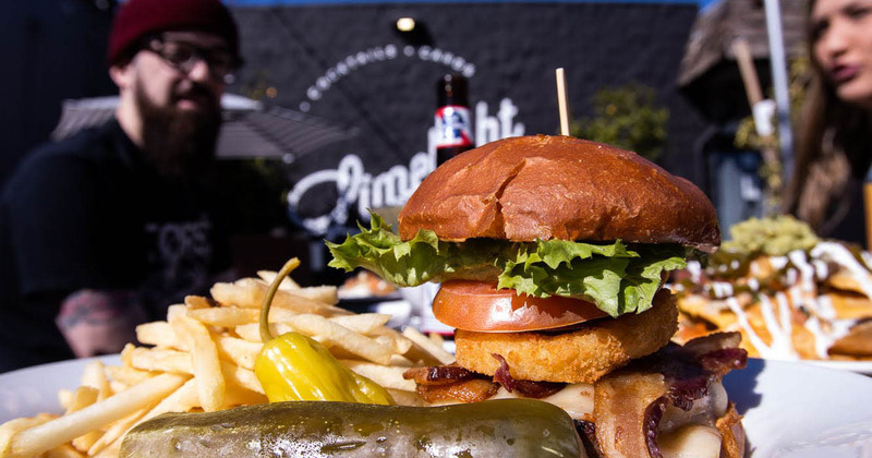 Burger with onion ring, served on a table outside