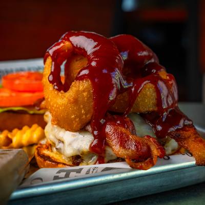 Cattleman Burger topped with bacon and onion rings, close-up.