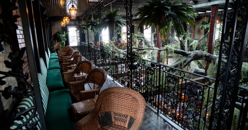 Indoor balcony with wicker chairs and a green cushioned bench