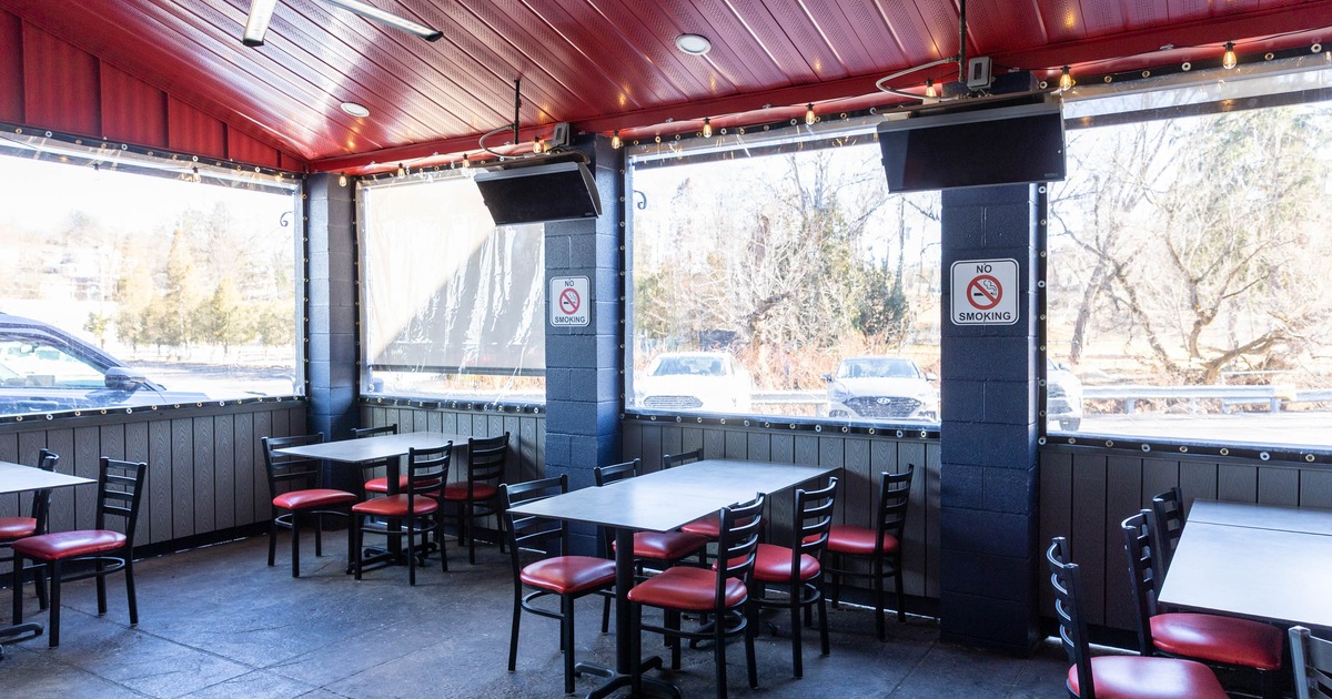 Covered outdoor restaurant seating area with tables, chairs