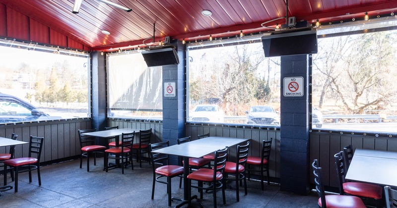 Covered outdoor restaurant seating area with tables, chairs