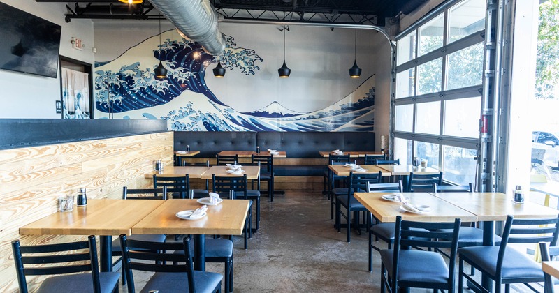Interior seating area with chairs and tables, with "The Great Wave off Kanagawa" mural