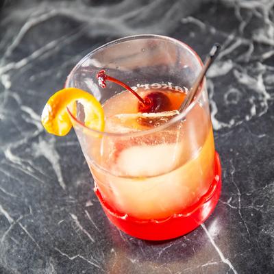 Old Fashioned cocktail with a cherry and orange peel garnish.