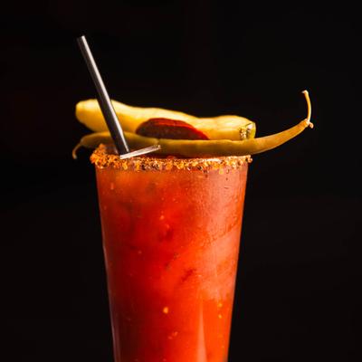 Red Caesar cocktail placed on a wooden table against a dark background.