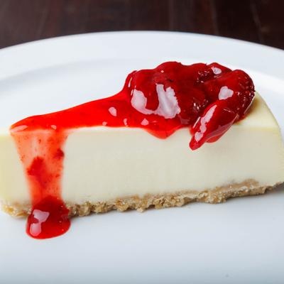 Cheesecake slice topped with strawberry sauce.