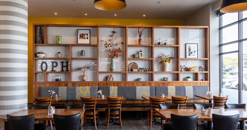 Cafe interior with wooden tables, black chairs, and upholstered bench