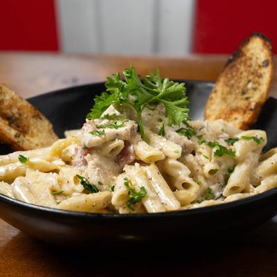 A bowl of creamy penne pasta with toast.