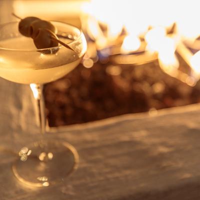 A cocktail in a glass next to fire patio