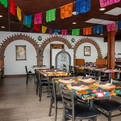 Interior featuring table seating, colorful banners and brick arched wall decor.