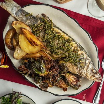 Roasted branzino served with potatoes and brussels sprouts.