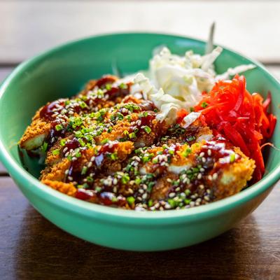 Breaded chicken cutlets with cabbage, sauce, and sesame seeds, side view.