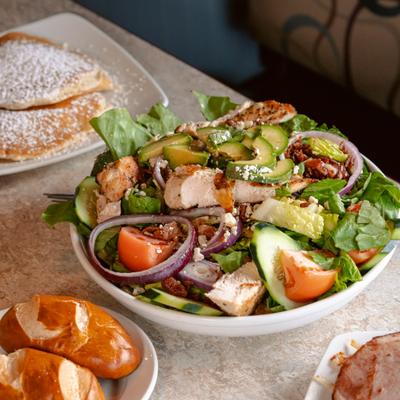 Cobb salad with grilled chicken, sliced avocado, red onions, tomatoes and cucumber.