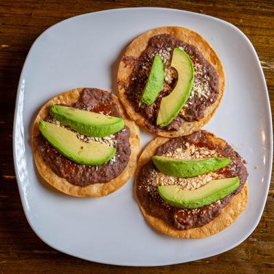 Honduran fried corn tortillas with refried beans, cheese, and avocado.