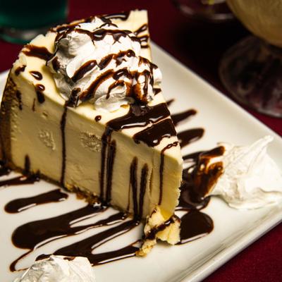 Cheesecake, with whipped cream and chocolate syrup.