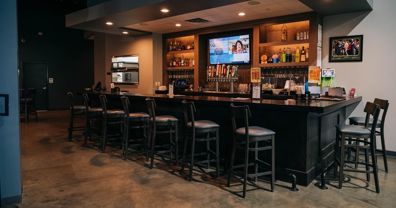 Bar, bartender, chairs and drink rack with tv's above