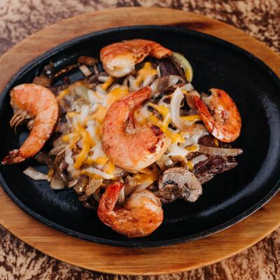 Marinated steak with jumbo shrimp, steamed vegetables, and Mexican rice.