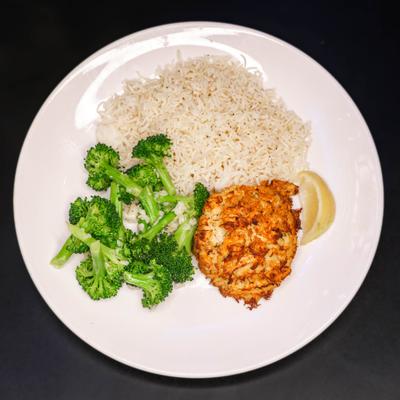 Crab cake served with rice and broccoli.