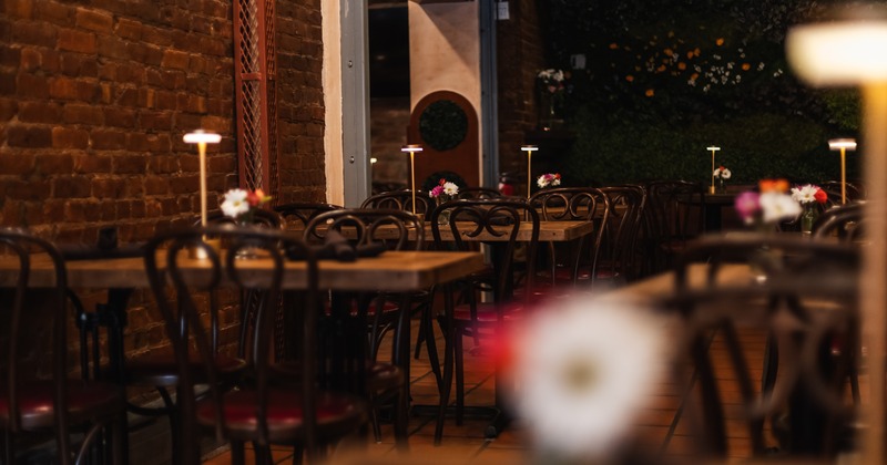 Dining room with wooden tables, brick walls, and soft lamp lighting