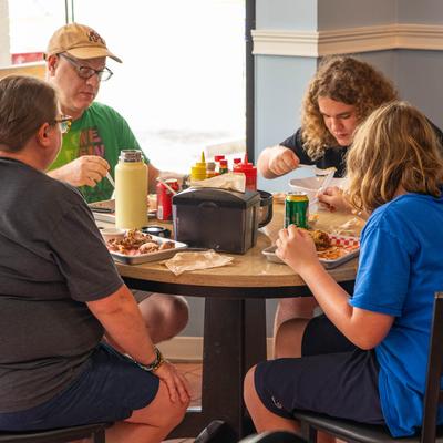 A family of four sits at a round table in the restaurant, enjoying a meal.