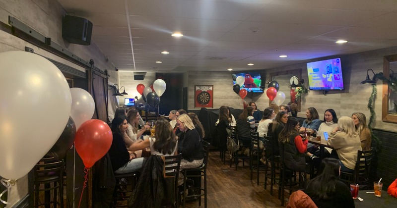 Guests seated at tables in a room decorated with colorful ballons