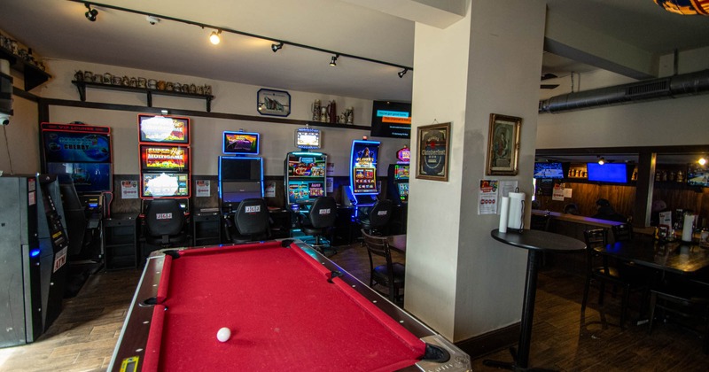 Interior, billiards table with red cloth, slot machines and ATM, beer can decorations