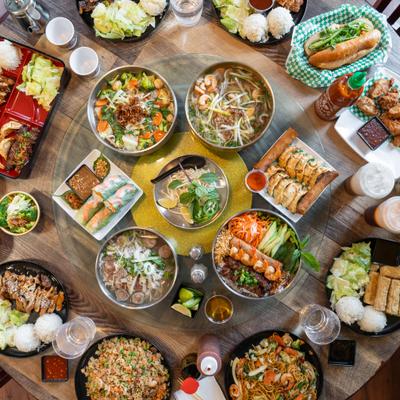 Large Vietnamese sharing spread featuring various traditional dishes, overhead view.