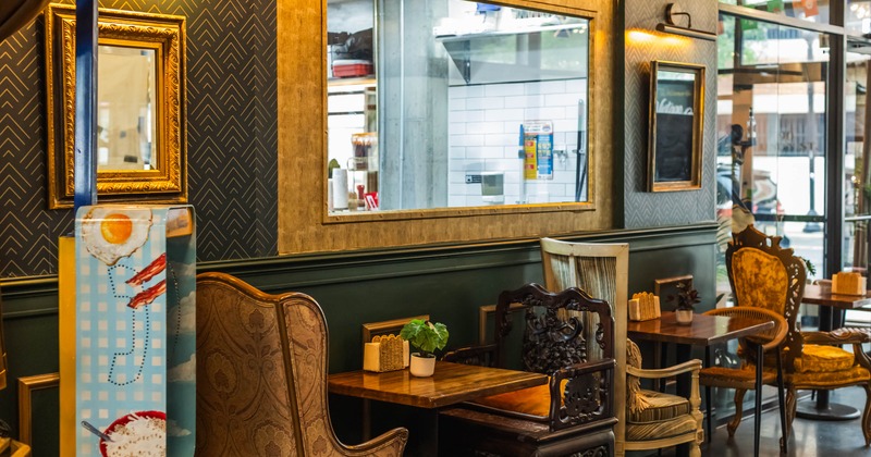 Cozy interior - a textured wall with a mirror, stylish seating and polished wooden tables