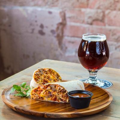 Smothered breakfast burrito with salsa on the side and a beer.