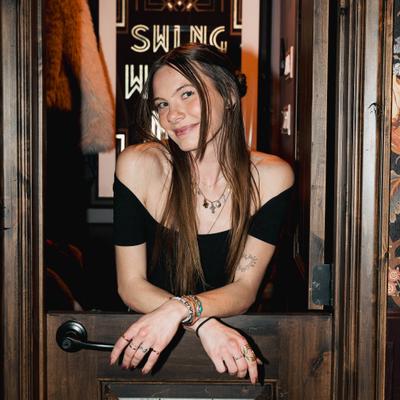 A person leans on a half-door, smiling warmly.