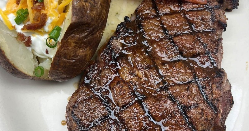 Grilled steak served with bacon wraped shrimp and loaded baked potato