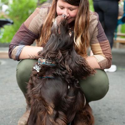 Person kneeling while a dog reaches up affectionately.