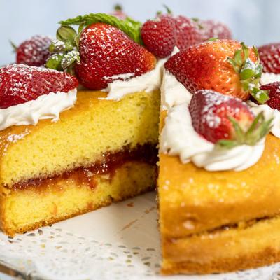 Victoria sponge cake with strawberry jam filling, whipped cream, and fresh strawberries on top.