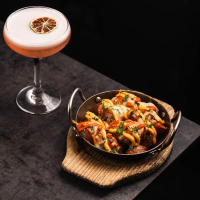 Patatas bravas served alongside a cocktail in a coupe glass.