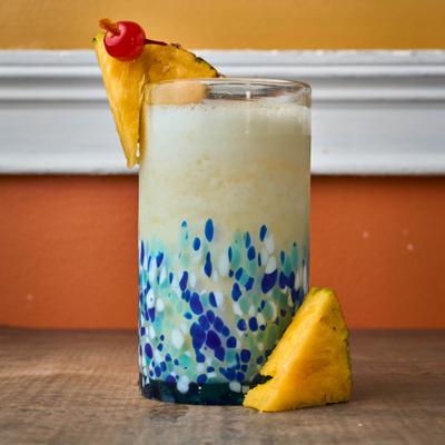 Pina Colada with pineapple and cherry garnish.