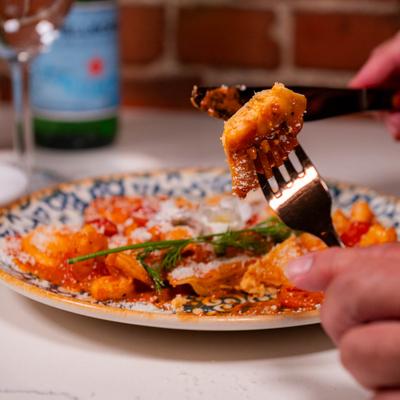 Hand holding a forkful of pasta above a plate.
