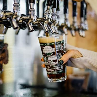A pint glass being filled with beer from a tap.