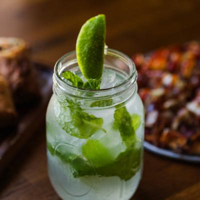 Mojito cocktail served in a mason jar with lime wedge as a garnish.