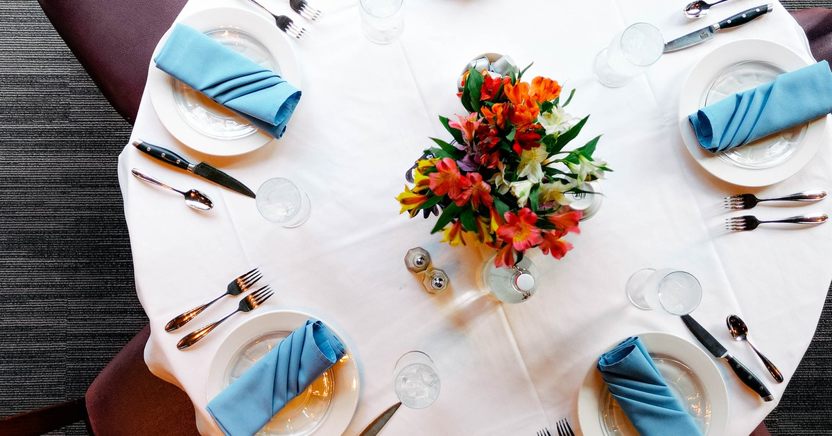 A table with blue napkins, and silverware, decorated with flowers, top view