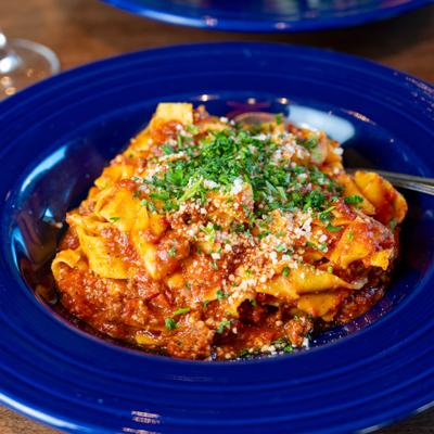 Pappardelle pasta with beef ragu on a blue plate.