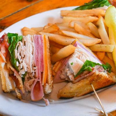 Stevie's Club sandwich with turley and ham, served with fries and a pickle.