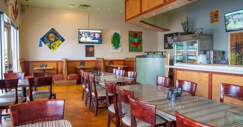 Interior, lined up dining tables, booths by a wall decorated with artworks, counter
