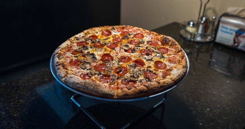 Whole pepperoni and mushroom pizza served on the table