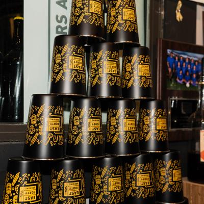 Stack of black and yellow “East Forty Brewing” cups..