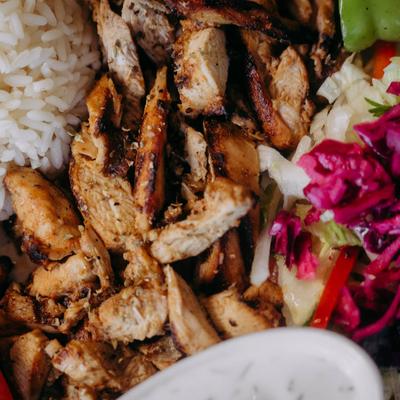 A close-up of grilled chicken with rice and pickled vegetables.