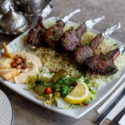 Lamb chops served with rice, salad and hummus.