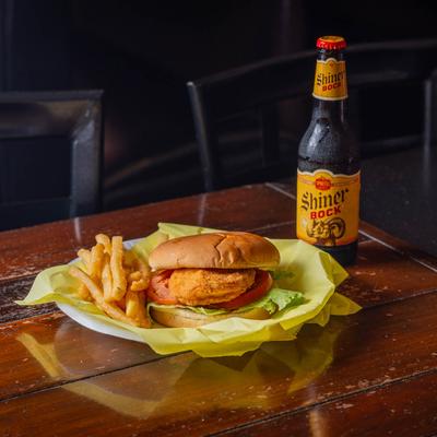 Chicken breast sandwich with fries and beer.