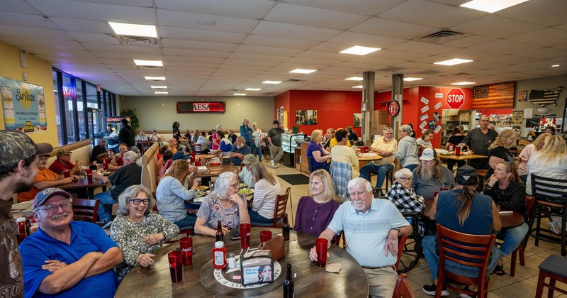 Group of friends posing at a table in a busy restaurant