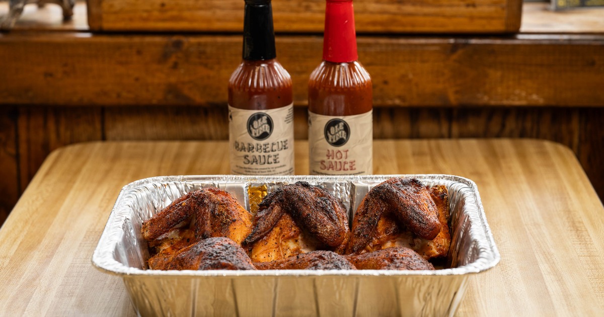 BBQ Chicken arranged in a foil catering pan and served with sauces
