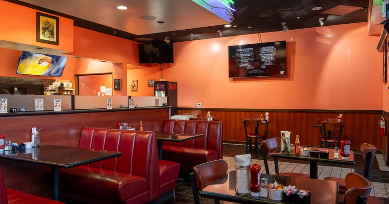 Restaurant interior with red booths, orange walls and neon ceiling lights.
